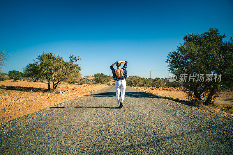 Walking on empty road. Woman on vacations. Arid climate